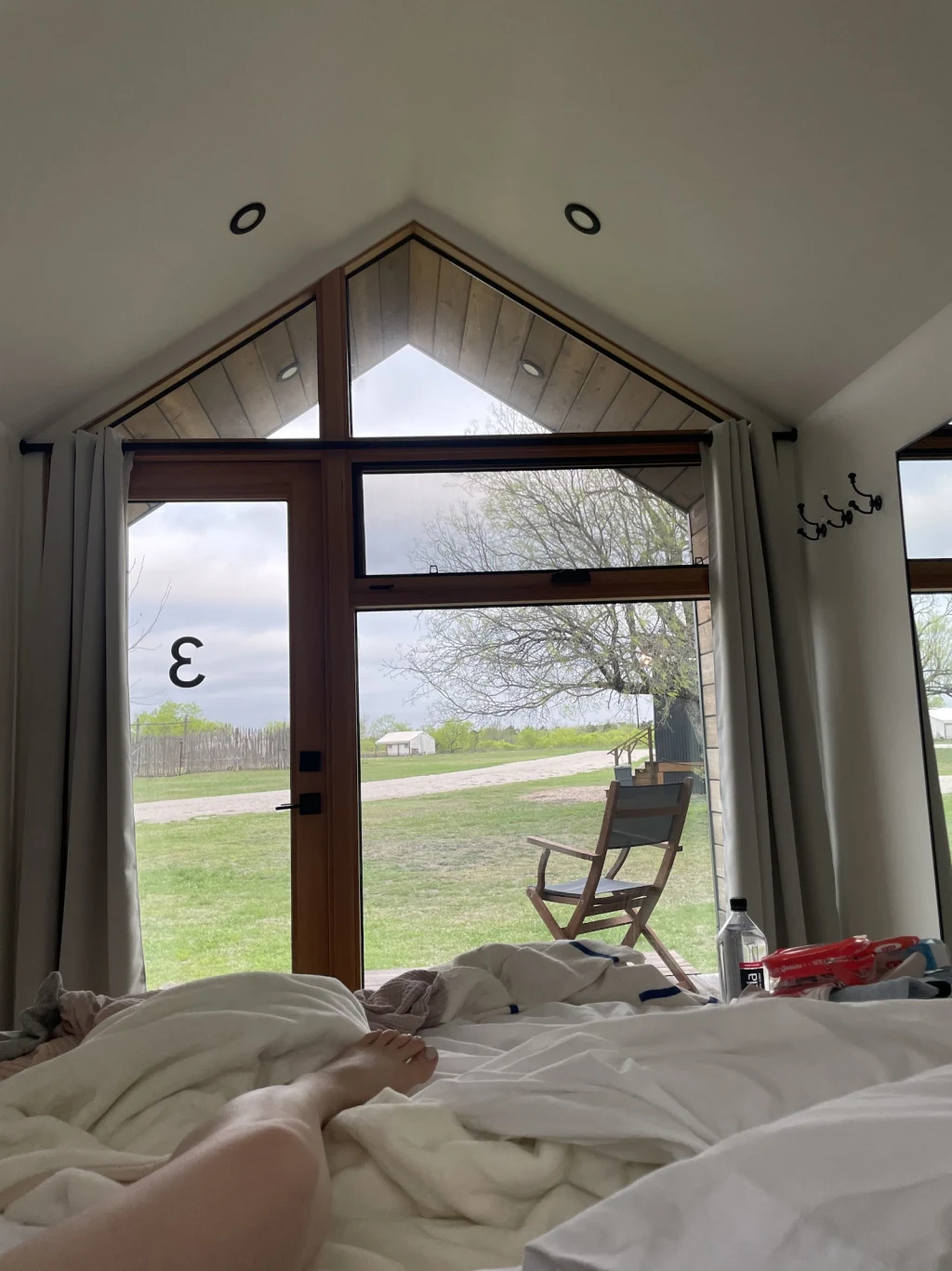 Cabin interior looking out a tall window onto the ranch pasture