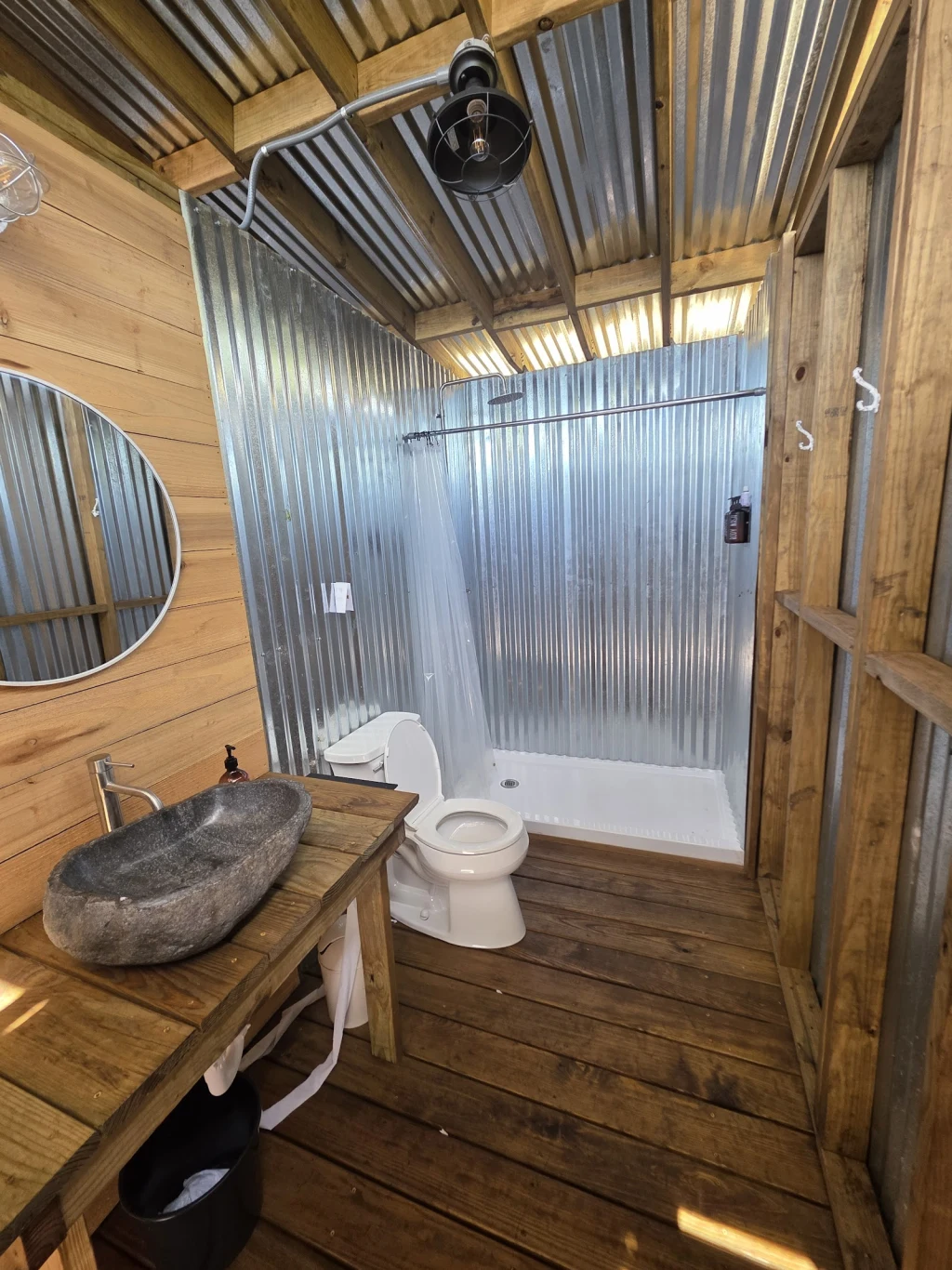 Outdoor shower and stone sink in a corrugated metal bathhouse