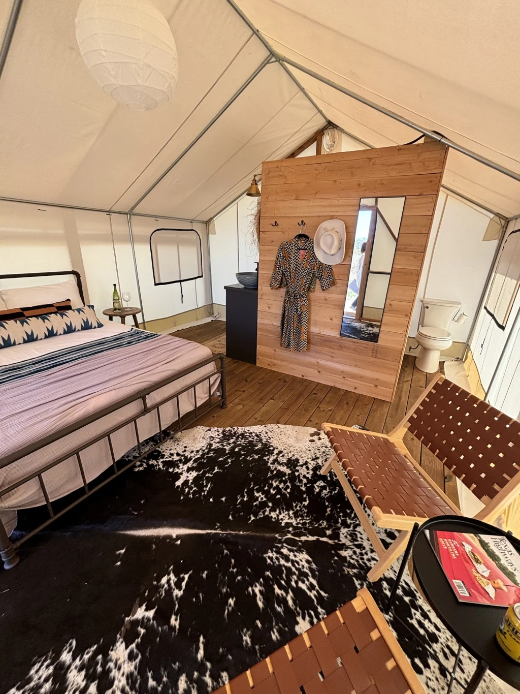 Safari tent with cowhide rug and robe hanging on cedar wall