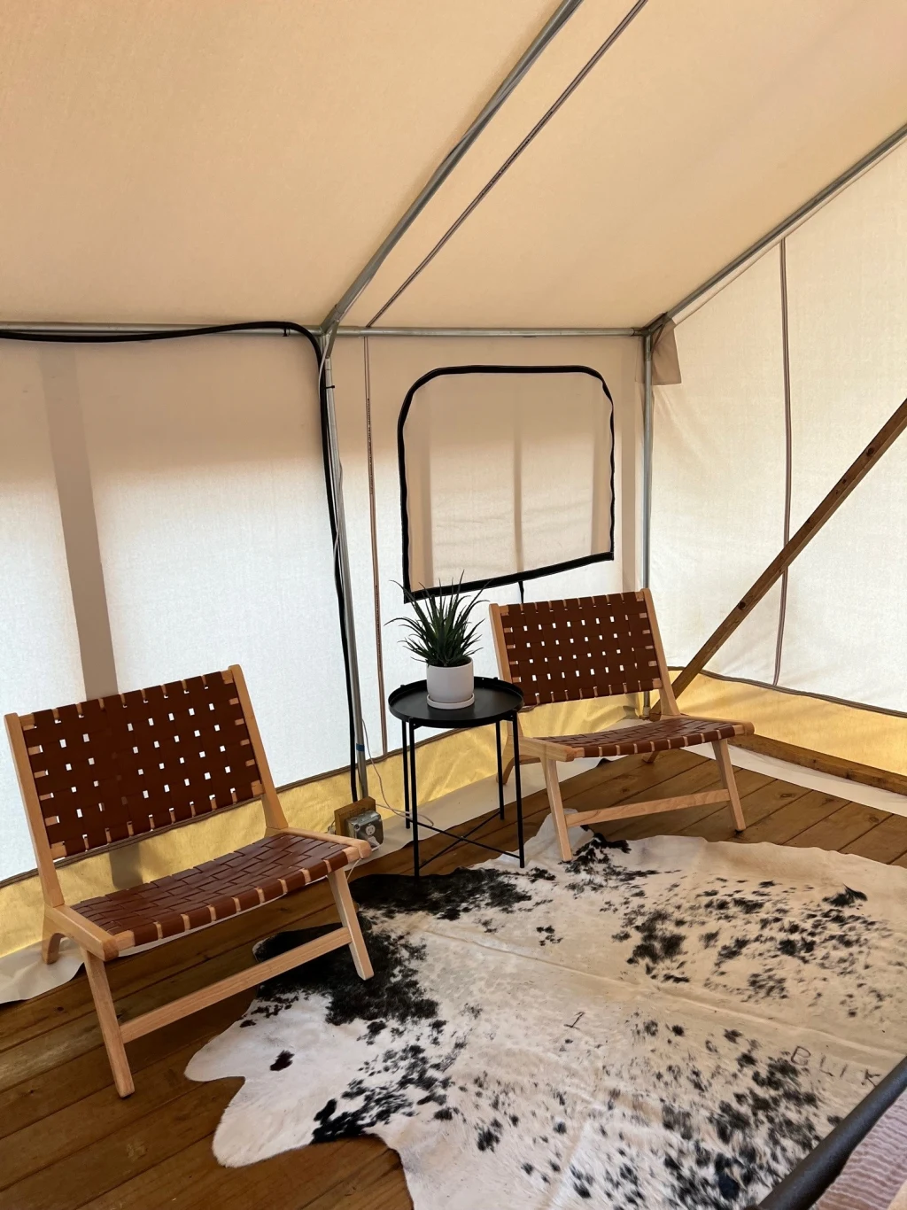 Safari tent lounge area with woven chairs and cowhide rug
