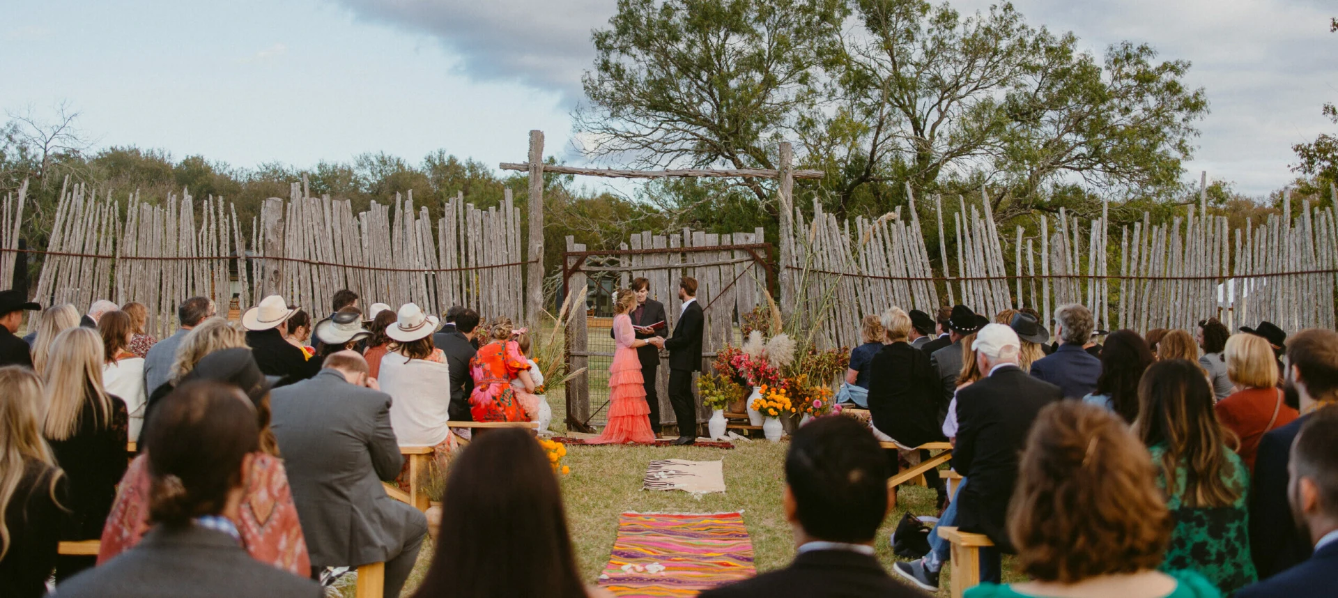 Evening wedding reception under string lights at Rancho Moonrise with dinner tables and golden Texas sunset