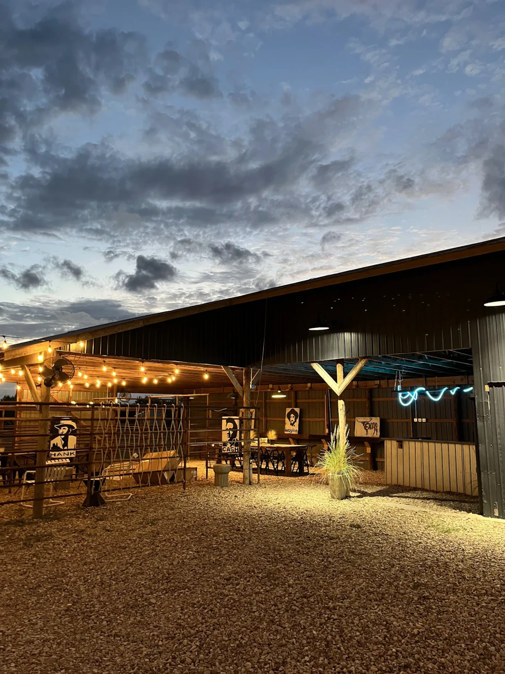 Event Barn at dusk with string lights and neon bronc sign at Rancho Moonrise