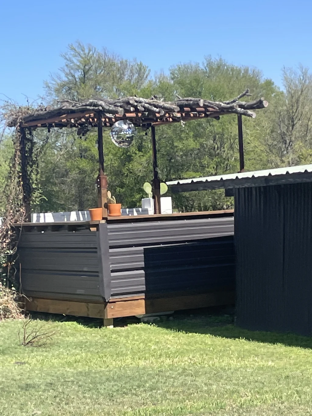Outdoor bar with disco ball under a branch pergola at Rancho Moonrise