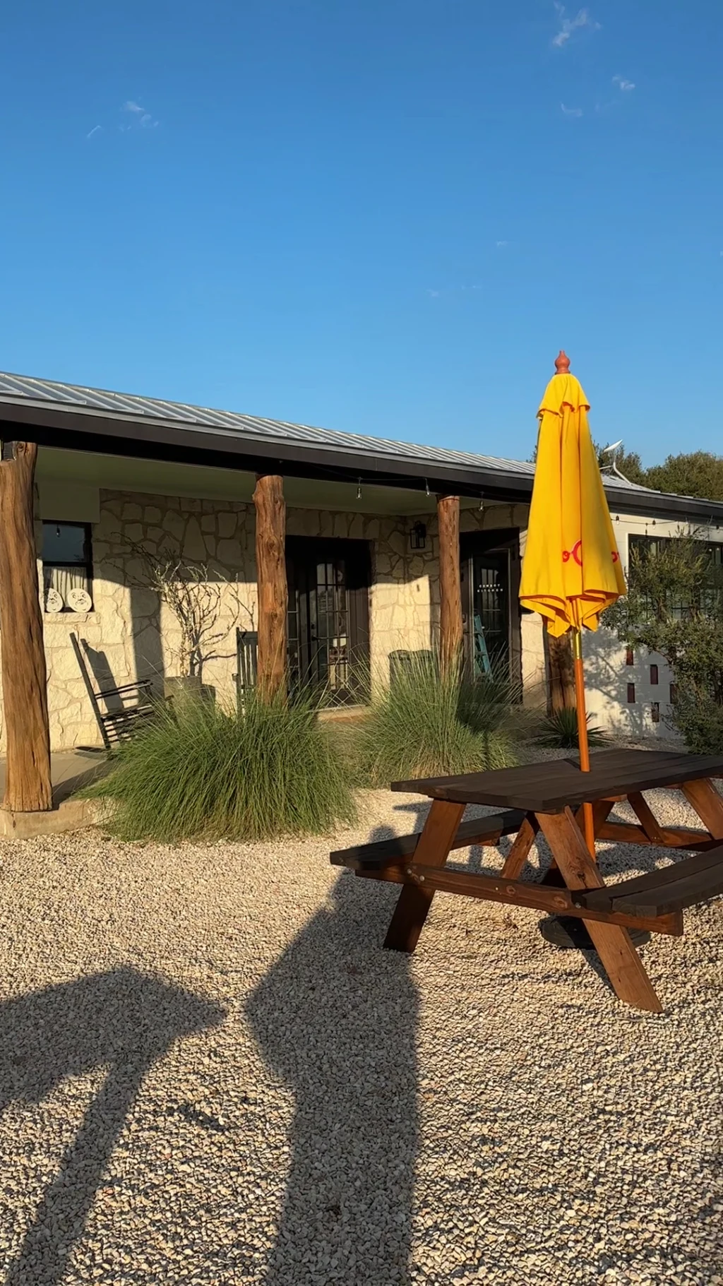Stone building porch with yellow umbrella picnic table at Rancho Moonrise