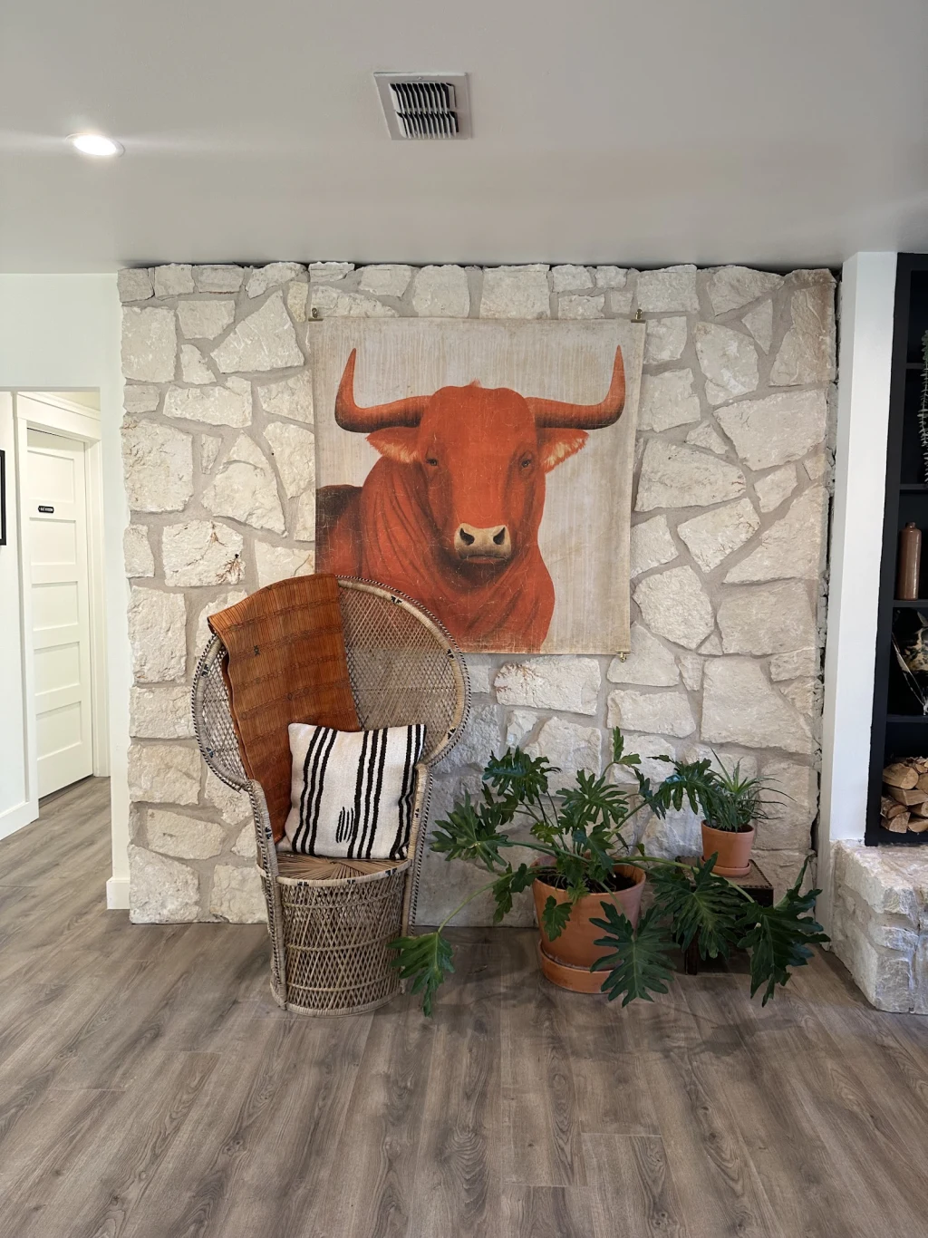 Red bull painting on stone wall beside a peacock chair in The Lodge