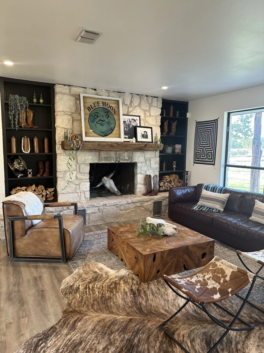 Inside The Lodge at Rancho Moonrise — stone fireplace, leather couches, and Blue Moon wall art in the social heart of the ranch
