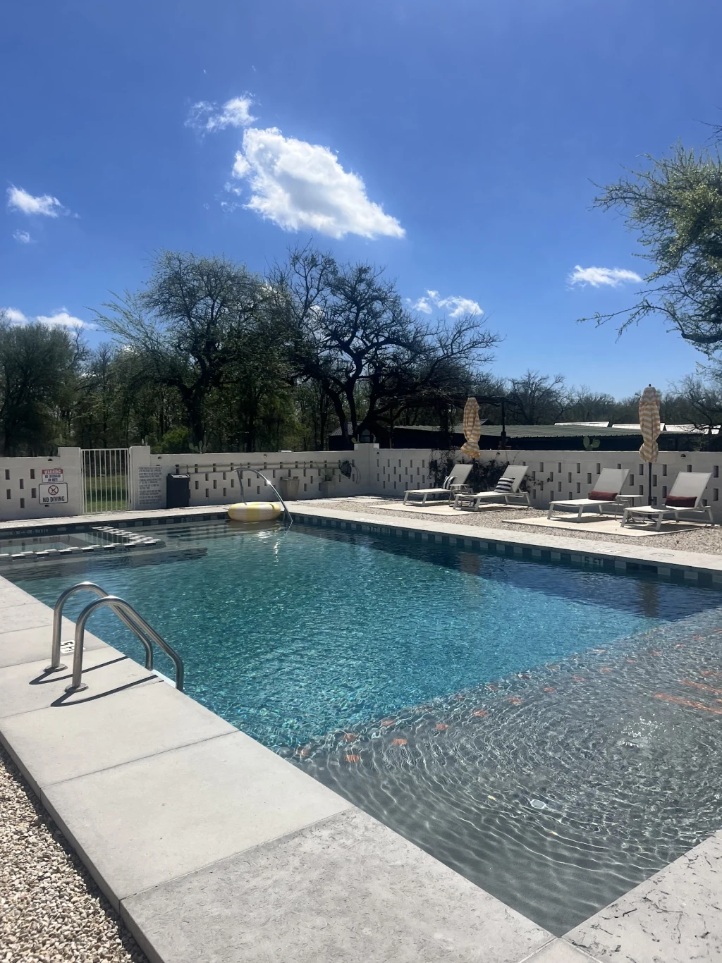 Overview of the pool area with striped umbrellas and lounge chairs at Rancho Moonrise